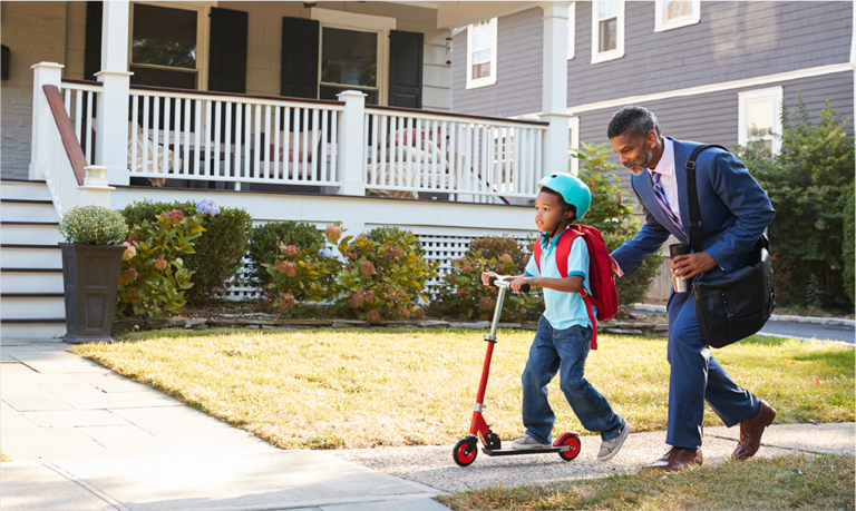 Photo of a man walking a little girl on a scooter